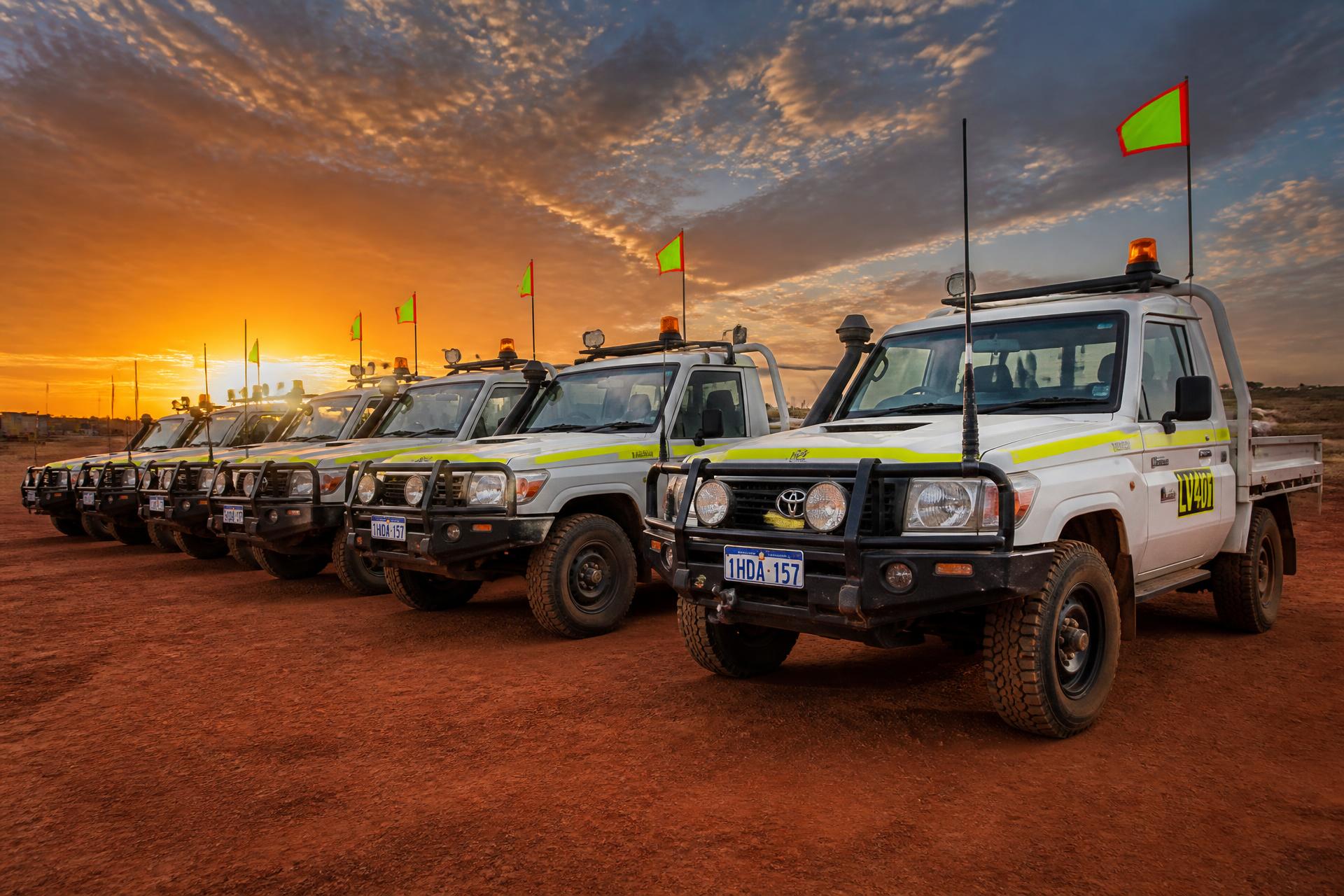 Line of Mine Spec Toyota LandCruiser vehicles on a red-dust Queensland site at sunset